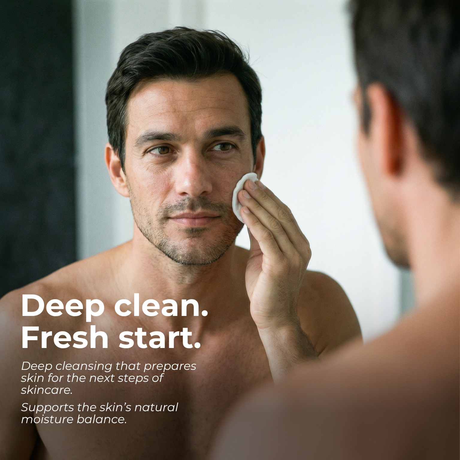 Man cleansing his face with a cotton pad in the mirror